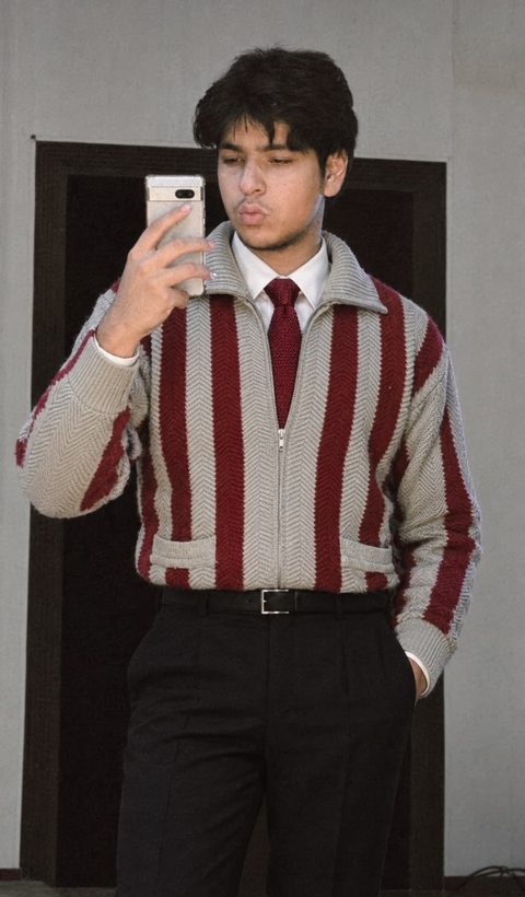 Moaaz Ali in a striped sweater and tie