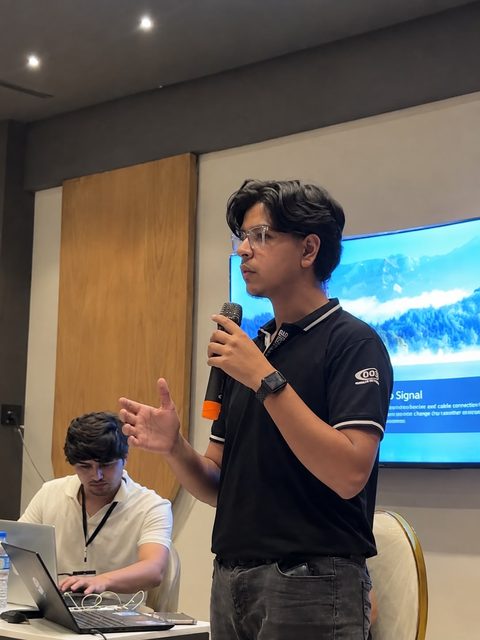 Moaaz Ali speaking into a microphone at a tech event