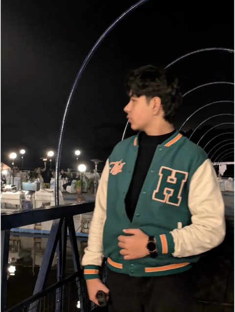 Moaaz Ali in a varsity jacket at night